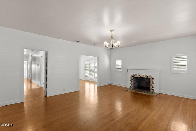 unfurnished living room with plenty of natural light, a chandelier, and hardwood / wood-style flooring