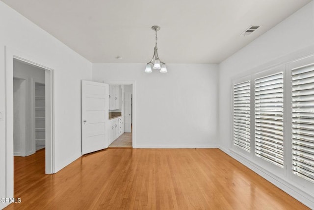 unfurnished dining area with light hardwood / wood-style floors and a notable chandelier