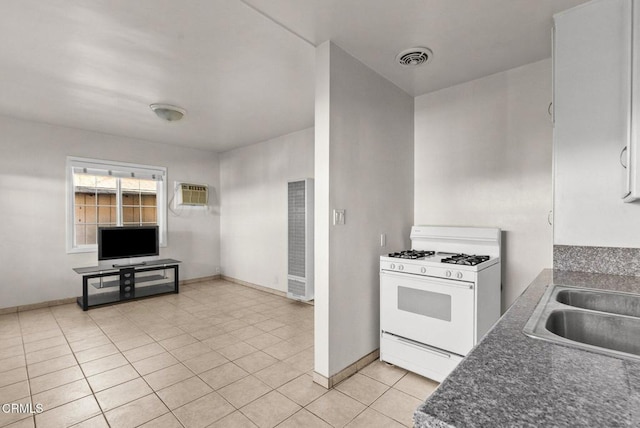 kitchen featuring white gas stove, light tile patterned flooring, a wall mounted air conditioner, and sink