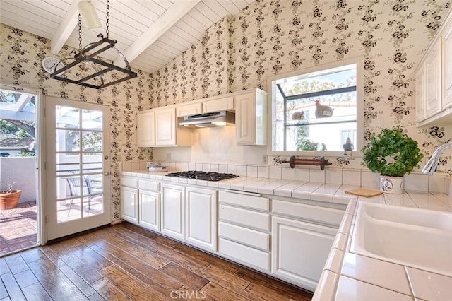 kitchen featuring white cabinets, tile counters, vaulted ceiling with beams, dark hardwood / wood-style floors, and sink