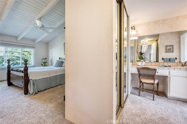 carpeted bedroom featuring sink, ceiling fan, and vaulted ceiling with beams