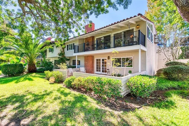 back of property with a lawn and a balcony