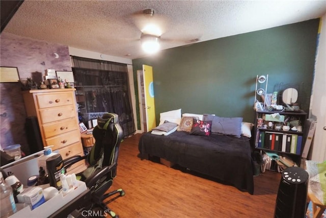 bedroom featuring hardwood / wood-style flooring, ceiling fan, a closet, and a textured ceiling