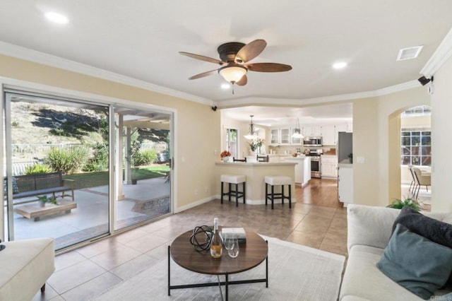 tiled living room featuring ceiling fan and ornamental molding