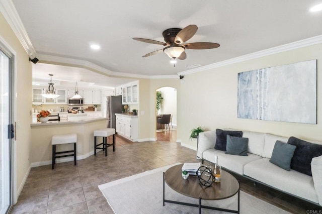 tiled living room with ceiling fan and crown molding