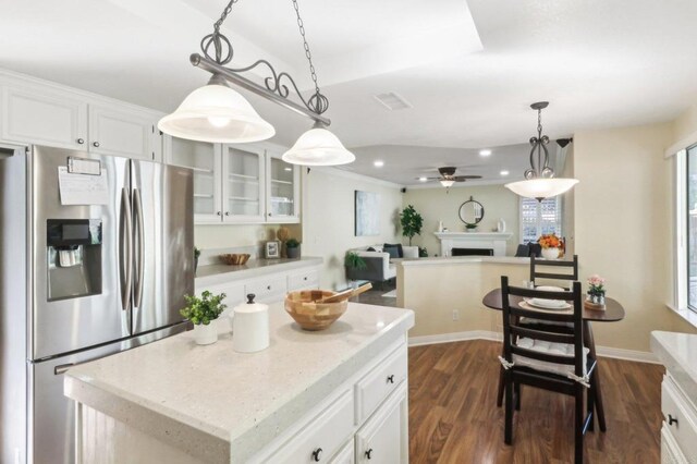 kitchen featuring white cabinets, dark hardwood / wood-style flooring, stainless steel fridge, and a kitchen island