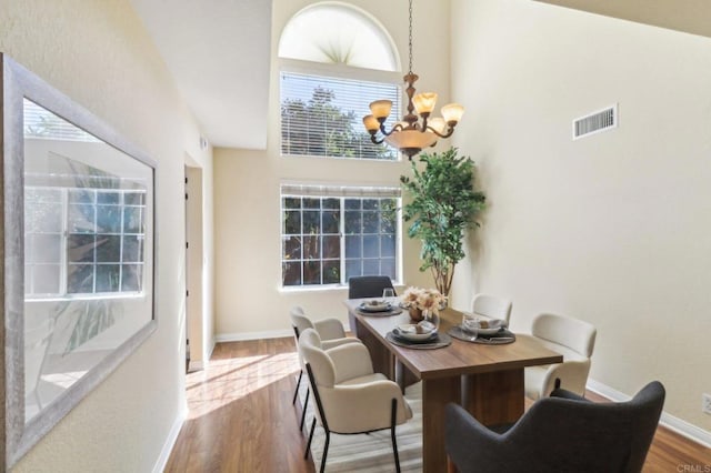 dining room with wood-type flooring, a high ceiling, and an inviting chandelier