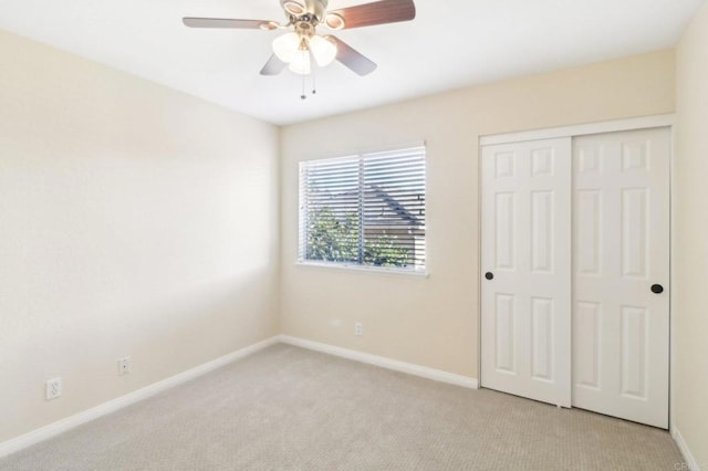 unfurnished bedroom with ceiling fan, light colored carpet, and a closet