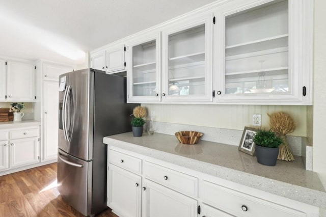 kitchen featuring stainless steel fridge with ice dispenser, white cabinetry, light stone counters, and light wood-type flooring