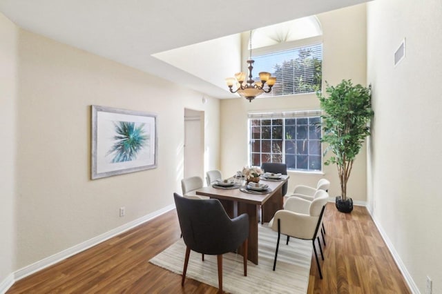 dining space featuring wood-type flooring and an inviting chandelier