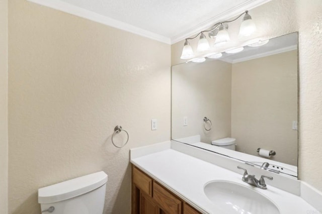 bathroom with toilet, vanity, and ornamental molding