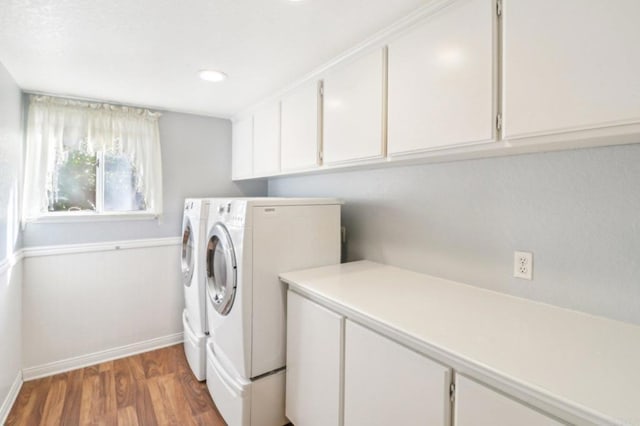 clothes washing area featuring washing machine and clothes dryer, cabinets, and dark hardwood / wood-style floors