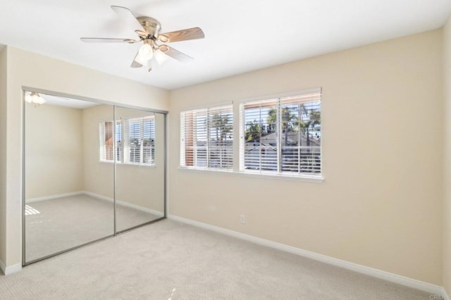 unfurnished bedroom with light colored carpet, a closet, and ceiling fan