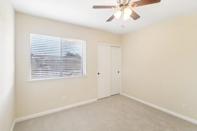 unfurnished bedroom featuring ceiling fan, light colored carpet, and a closet