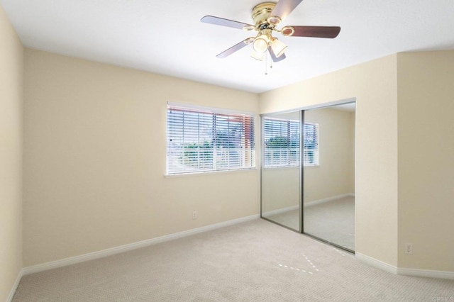 unfurnished bedroom featuring ceiling fan, a closet, and light carpet