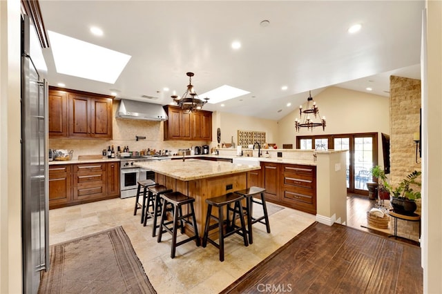 kitchen with kitchen peninsula, lofted ceiling with skylight, high end stainless steel range, and an inviting chandelier