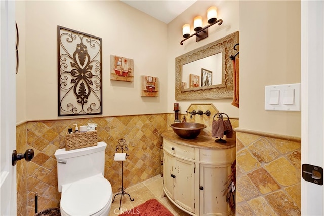 bathroom with vanity, toilet, and tile walls