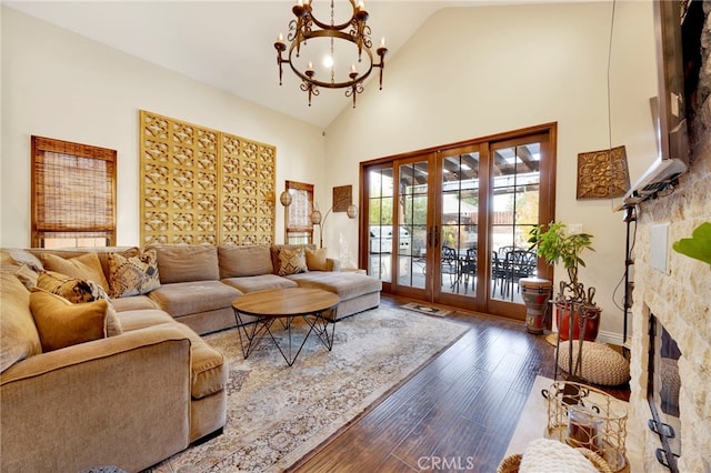 living room featuring french doors, an inviting chandelier, high vaulted ceiling, a fireplace, and hardwood / wood-style flooring