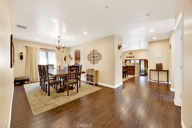 dining room with dark hardwood / wood-style floors and an inviting chandelier