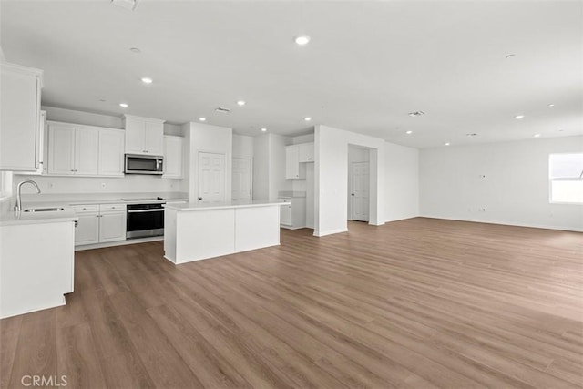 kitchen with a sink, open floor plan, light countertops, appliances with stainless steel finishes, and a center island