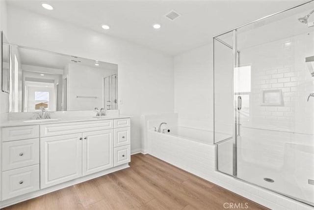 full bath with a garden tub, a sink, a shower stall, and wood finished floors