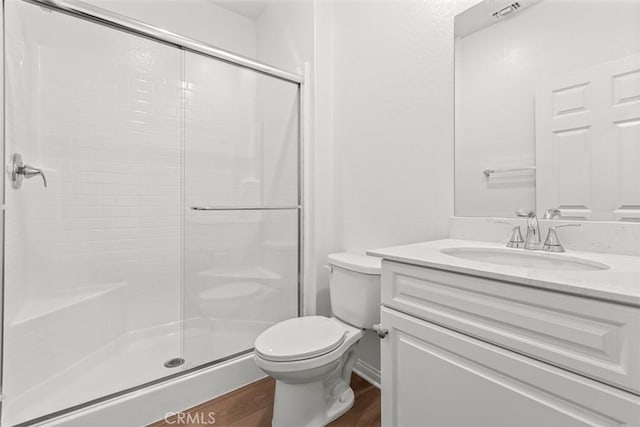 full bathroom with a stall shower, visible vents, toilet, wood finished floors, and vanity