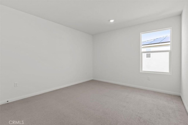 unfurnished room featuring light colored carpet and baseboards