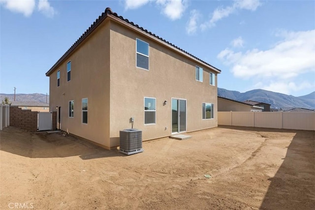 back of house featuring fence, cooling unit, a mountain view, and stucco siding