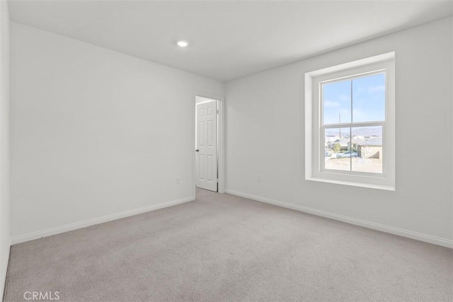 unfurnished room with light carpet, recessed lighting, and baseboards