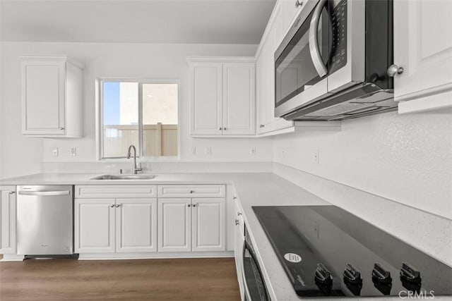 kitchen with stainless steel appliances, a sink, light countertops, and white cabinets