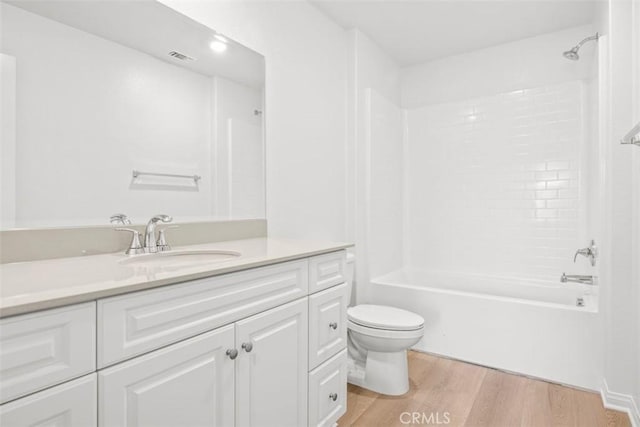 full bathroom featuring toilet, hardwood / wood-style flooring, vanity, and washtub / shower combination