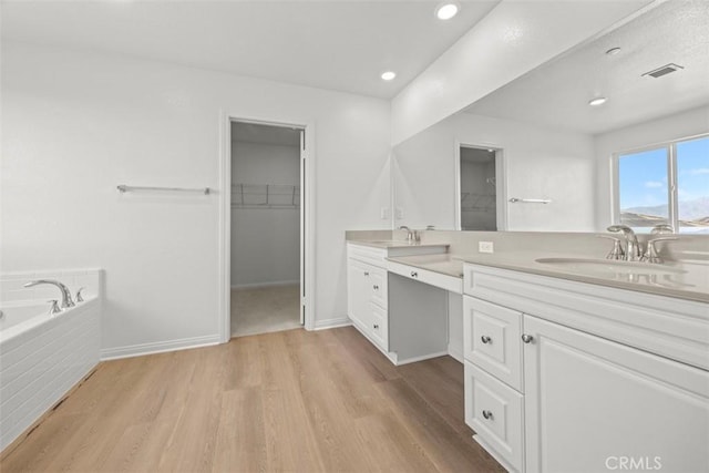 bathroom with tiled bath, hardwood / wood-style floors, and vanity