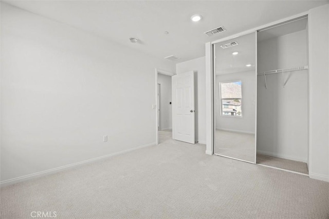 unfurnished bedroom featuring light carpet and a closet