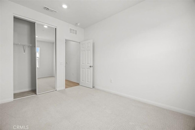 unfurnished bedroom featuring a closet and light colored carpet