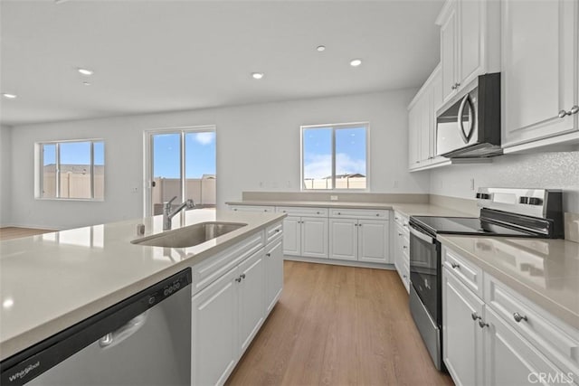 kitchen with white cabinets, a wealth of natural light, appliances with stainless steel finishes, and sink