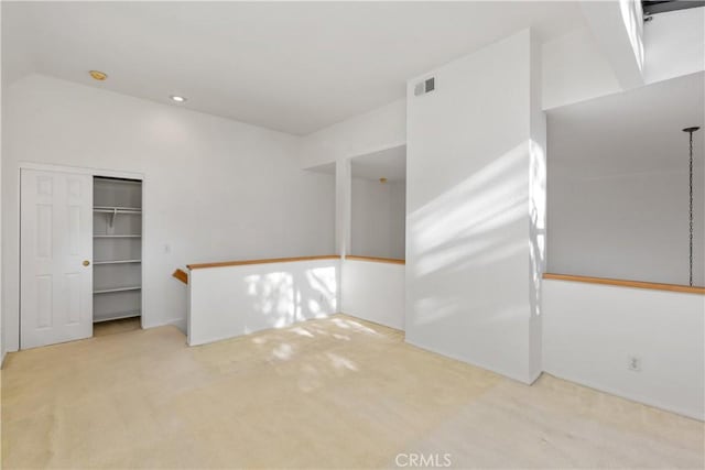 empty room featuring light carpet and vaulted ceiling