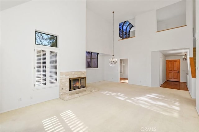 unfurnished living room with hardwood / wood-style floors, a towering ceiling, and a chandelier