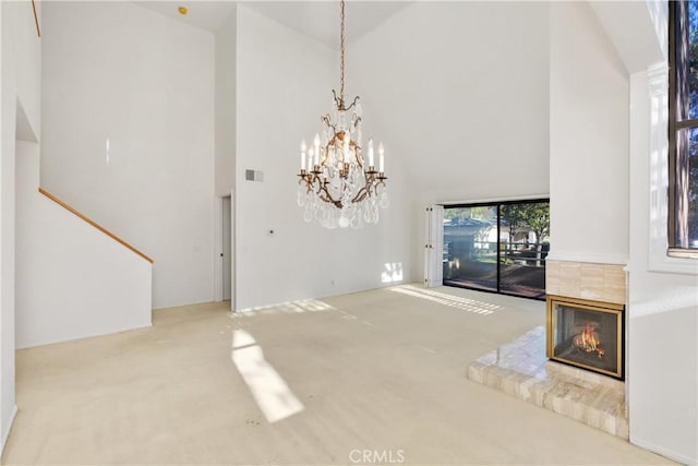 unfurnished living room featuring carpet floors, a fireplace, high vaulted ceiling, and an inviting chandelier