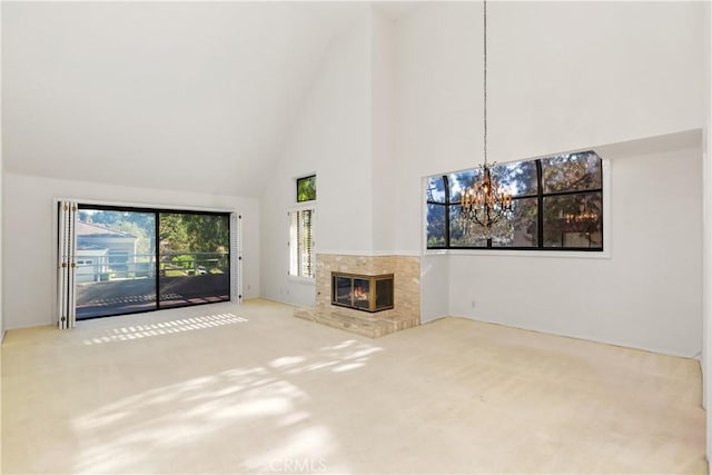 unfurnished living room featuring carpet, high vaulted ceiling, and a chandelier