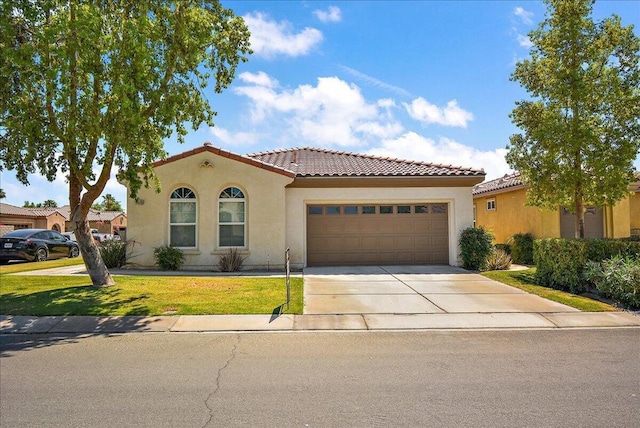 mediterranean / spanish house featuring a garage and a front yard