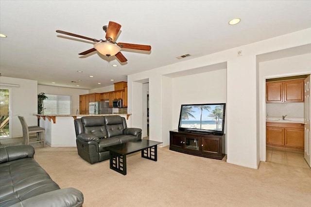 living room featuring light colored carpet, ceiling fan, and sink