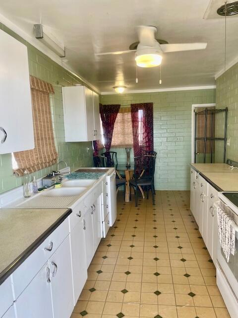 kitchen featuring white cabinetry, sink, light tile patterned floors, and white stove