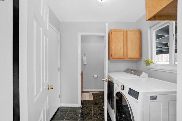 clothes washing area featuring washer and clothes dryer, cabinets, and dark tile patterned flooring