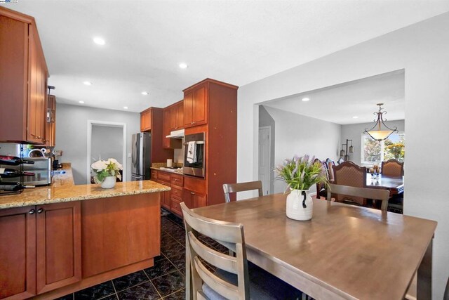 kitchen with decorative light fixtures, light stone countertops, and stainless steel appliances