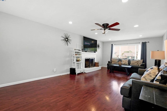 living room with ceiling fan, dark hardwood / wood-style flooring, and a brick fireplace