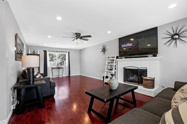 living room with wood-type flooring, a brick fireplace, and ceiling fan