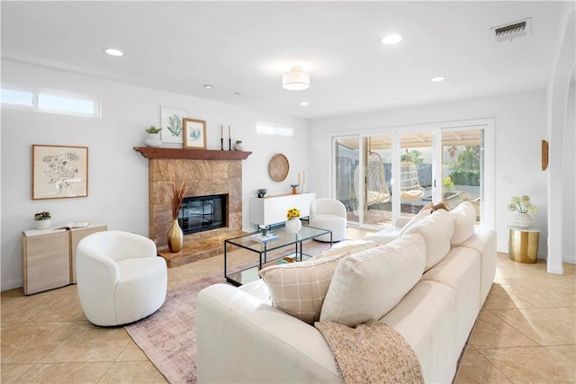 living room featuring a healthy amount of sunlight, light tile patterned floors, and a high end fireplace