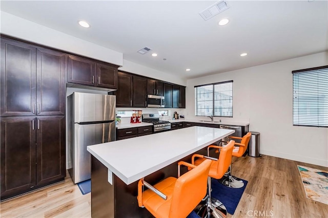 kitchen featuring sink, a center island, light hardwood / wood-style flooring, a kitchen bar, and appliances with stainless steel finishes