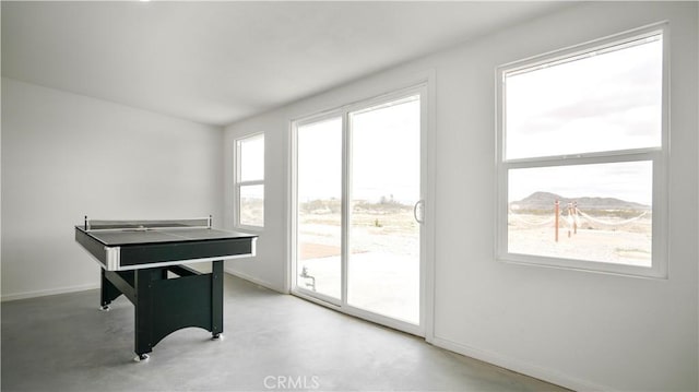 game room with a mountain view, concrete floors, and a healthy amount of sunlight