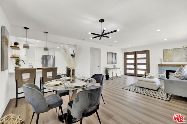 dining space featuring french doors, an inviting chandelier, and light wood-type flooring